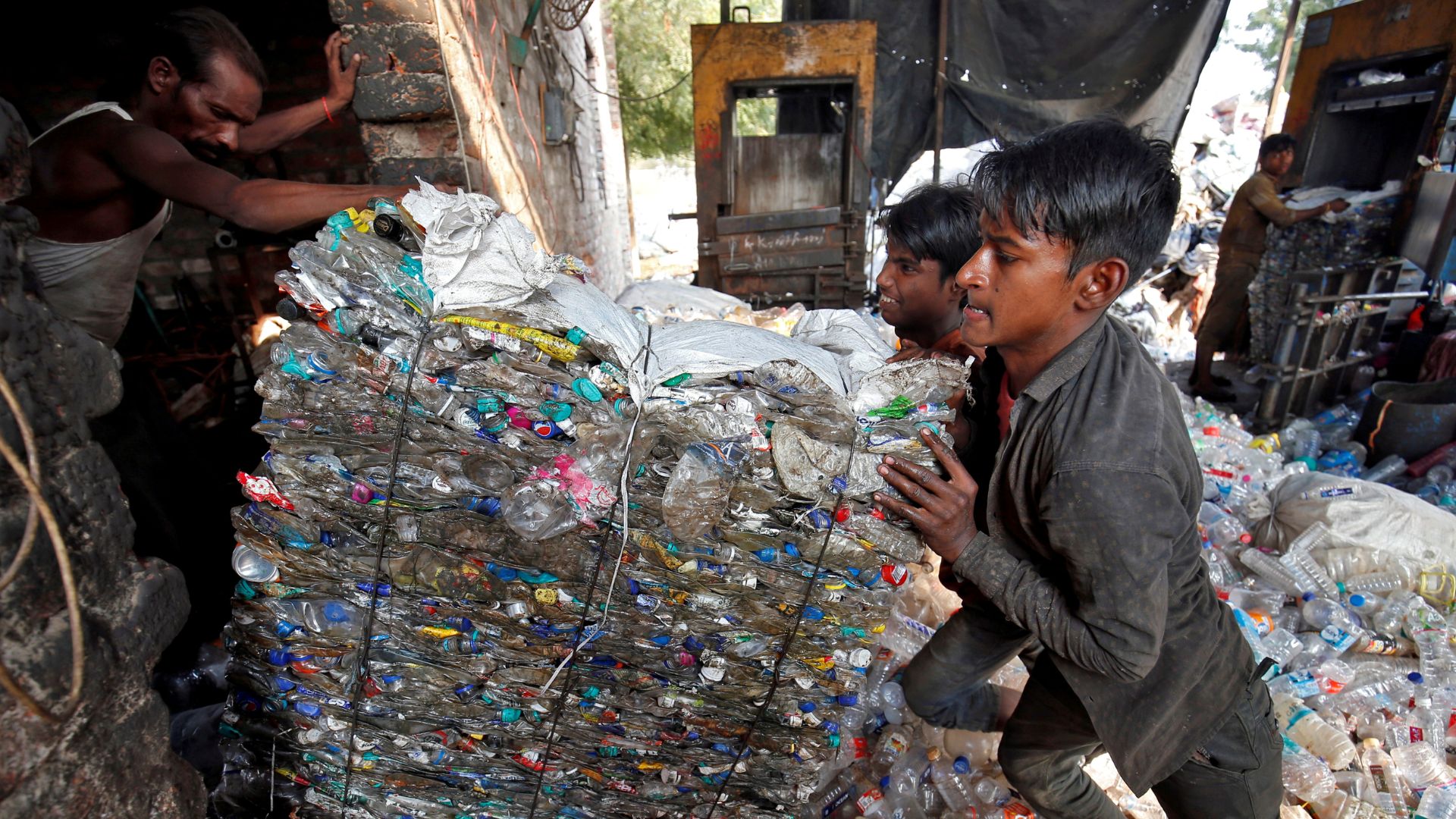 Workers push a bundle of crushed plastic bottles at a recycling factory in Ahmedabad, India, November 22, 2018. REUTERS/Amit Dave/File Photo