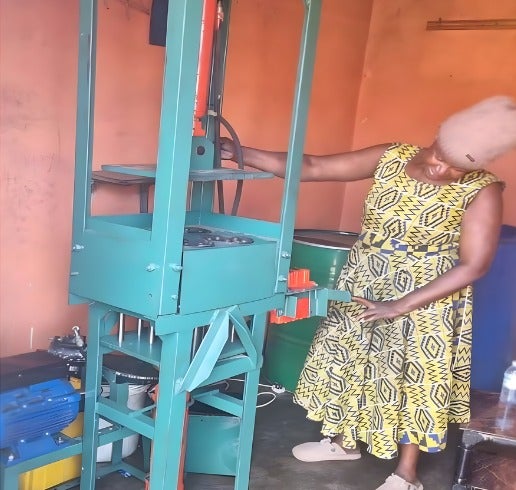 A woman operator tests the newly installed machine dual‐power briquette machine at one of the enterprises, preparing the site for active production.